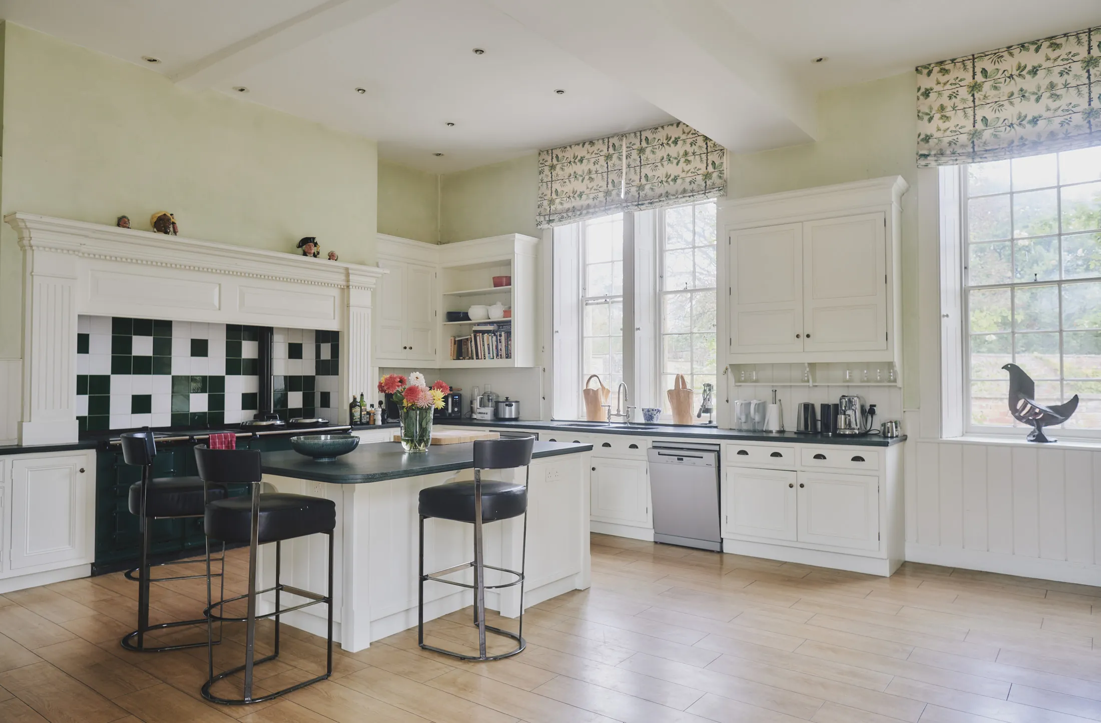 Bright country kitchen with white cabinetry, green metro tiles, and island seating at Havenwood luxury rental in The Cotswolds.