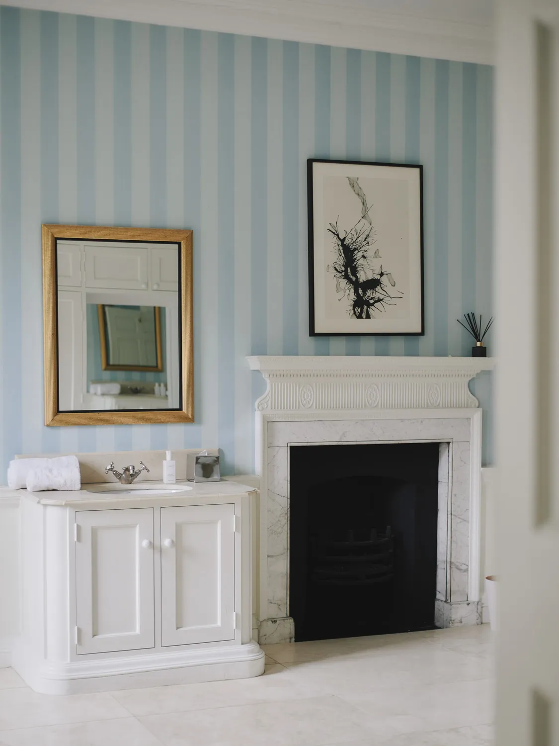 Period bathroom featuring marble fireplace and contemporary art at Havenwood exclusive short stay retreat in The Cotswolds.