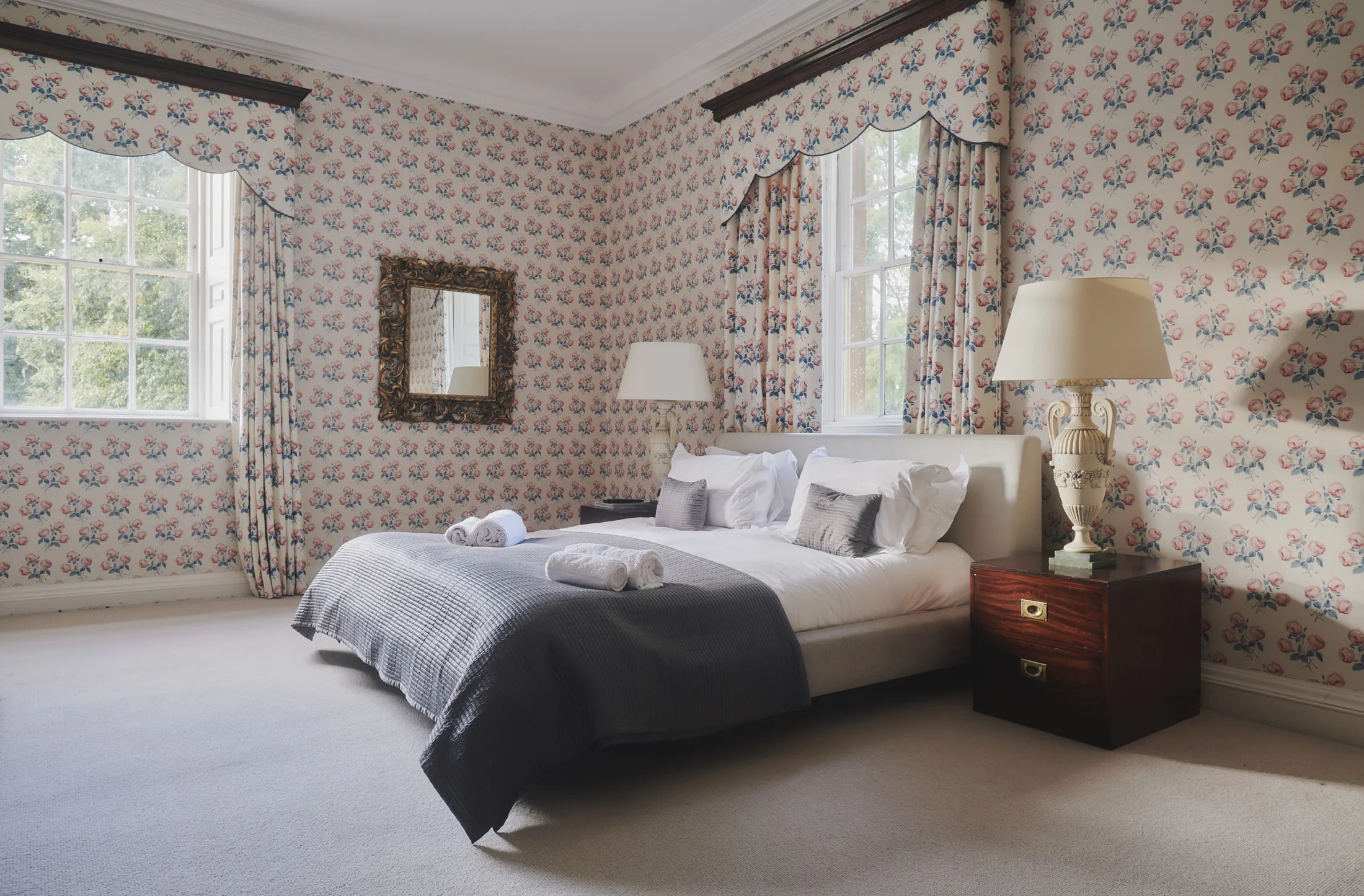 Elegant bedroom with floral wallpaper and period details at Havenwood luxury countryside rental in The Cotswolds.