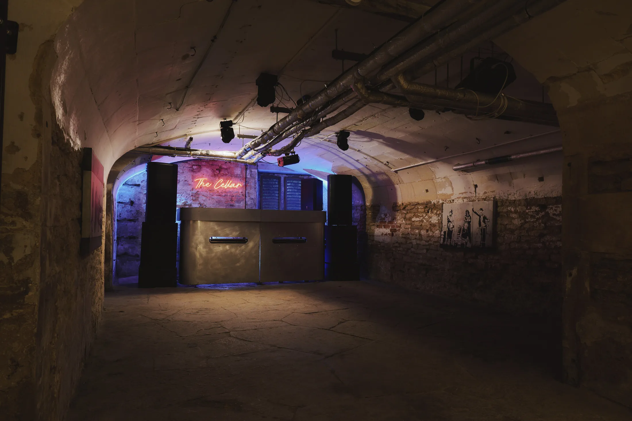 Atmospheric brick-vaulted cellar with DJ booth and mood lighting at Havenwood, a Domus Stay luxury short term rental.