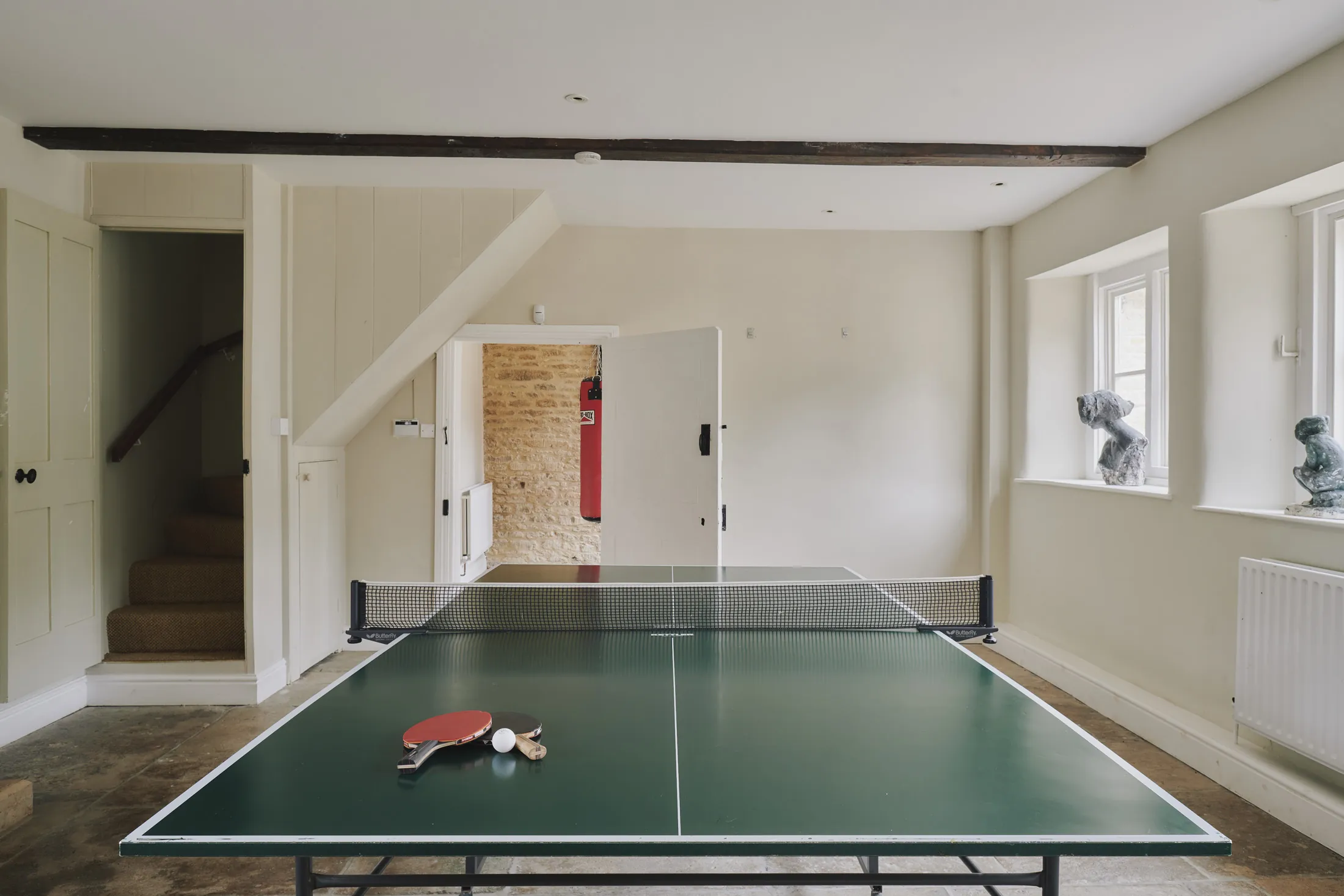 Light-filled games room with table tennis under tall windows at Havenwood exclusive short stay retreat in The Cotswolds.