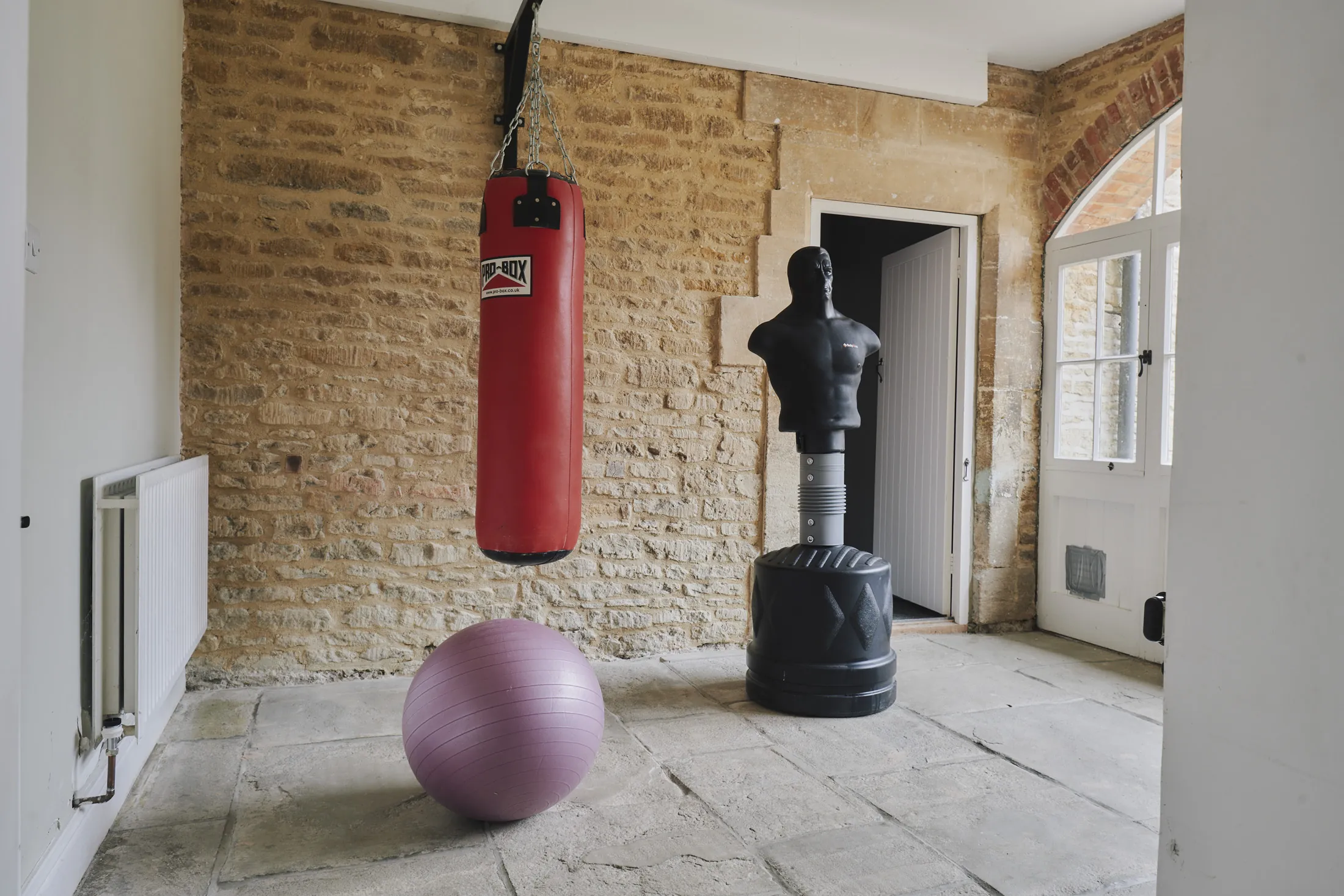 Private gym with boxing equipment and stone flooring at Havenwood, a Domus Stay luxury countryside property in The Cotswolds.