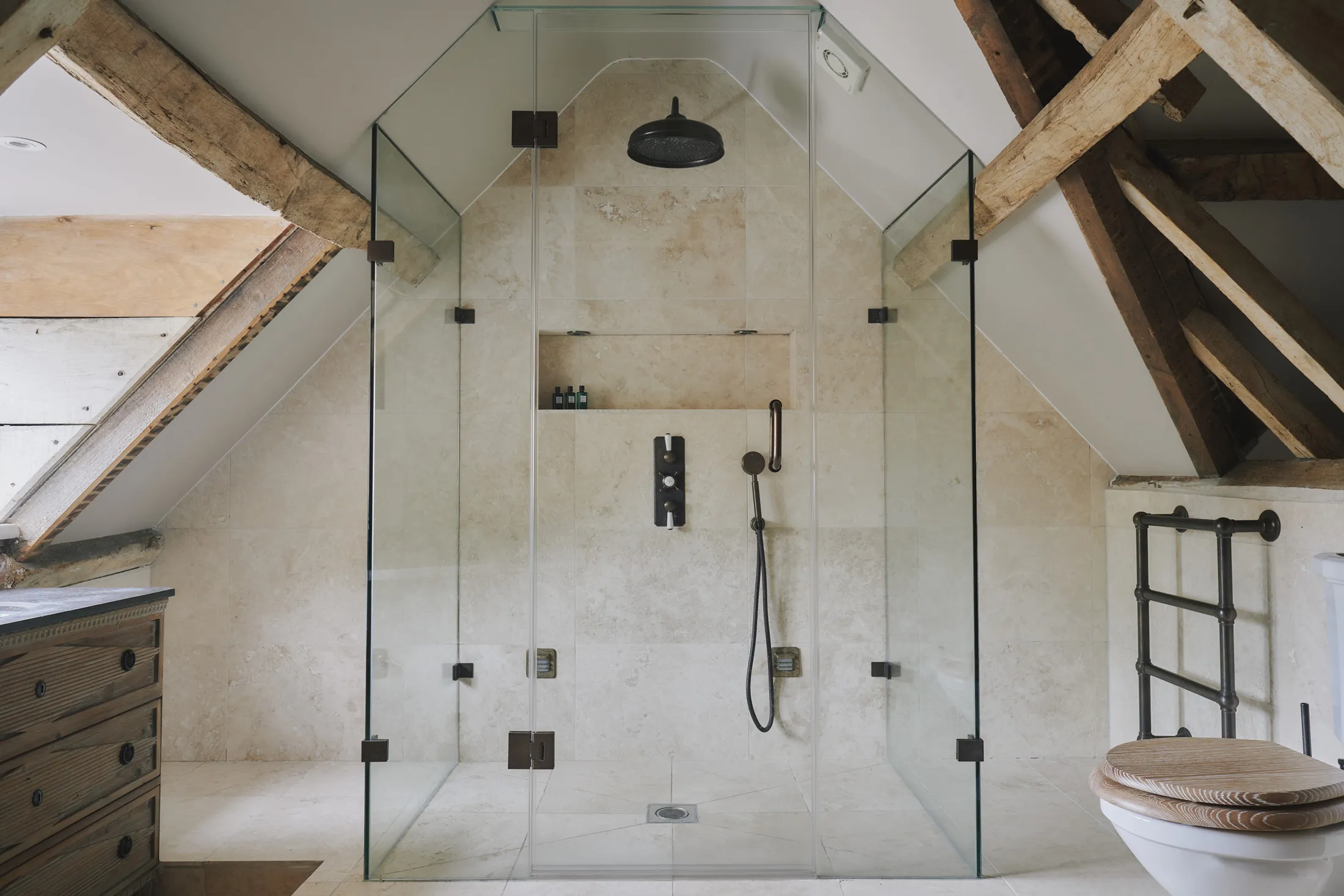 Attic bathroom with walk-in shower and reclaimed timber beams at Havenwood luxury short term property in The Cotswolds.