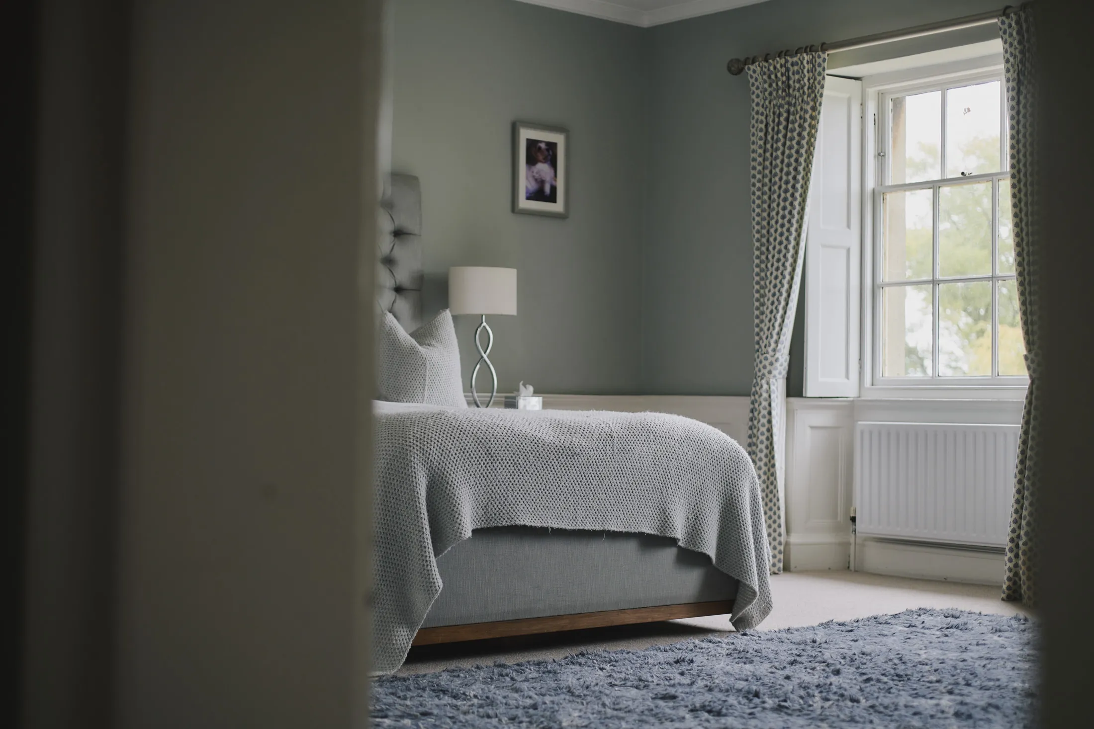 Bedroom with button-tufted headboard and textured rug at Havenwood, a Domus Stay luxury countryside property in The Cotswolds.