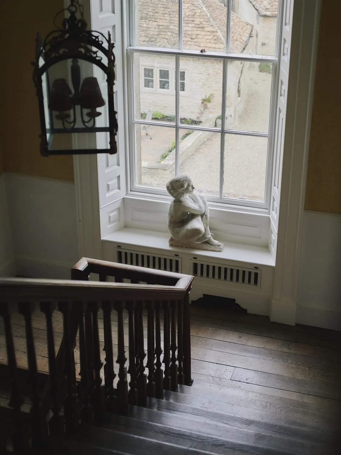 Stone sculpture on landing with views over cottage rooftops at Havenwood, an exclusive short stay property in The Cotswolds.