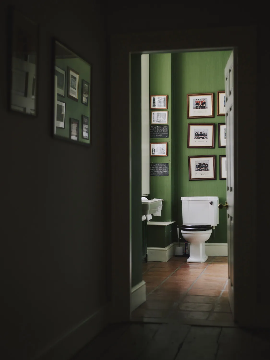 Vintage guest cloakroom with green walls and curated artwork at Havenwood luxury property for getaways in The Cotswolds.