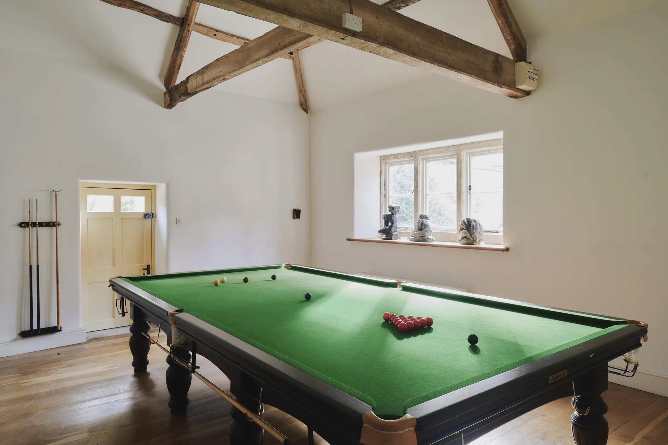 Billiards room with full-size snooker table beneath exposed beams at Havenwood exclusive short stay rental in The Cotswolds.