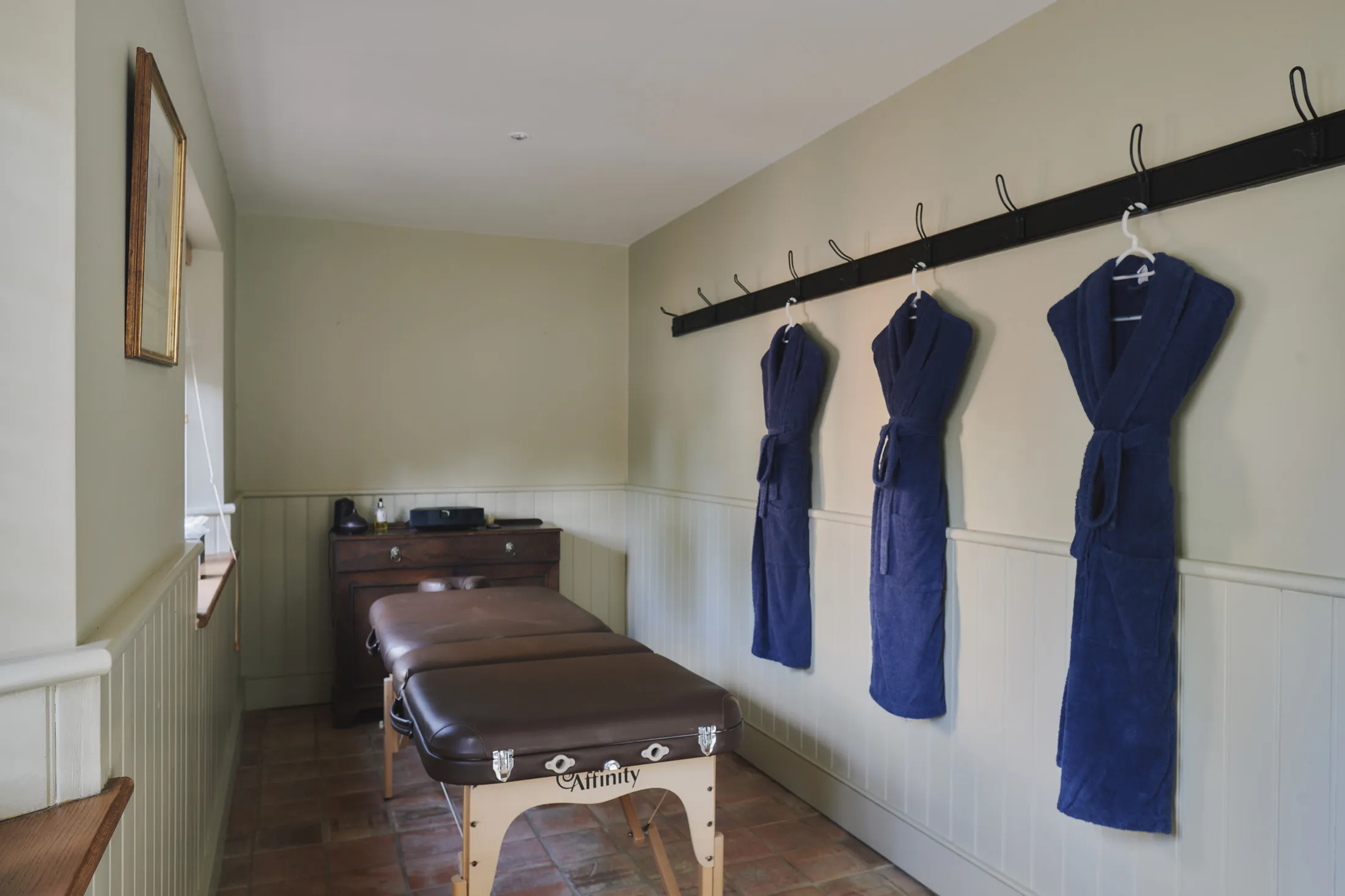 Tranquil treatment room with massage table and robes at Havenwood, a Domus Stay luxury property for wellness escapes.
