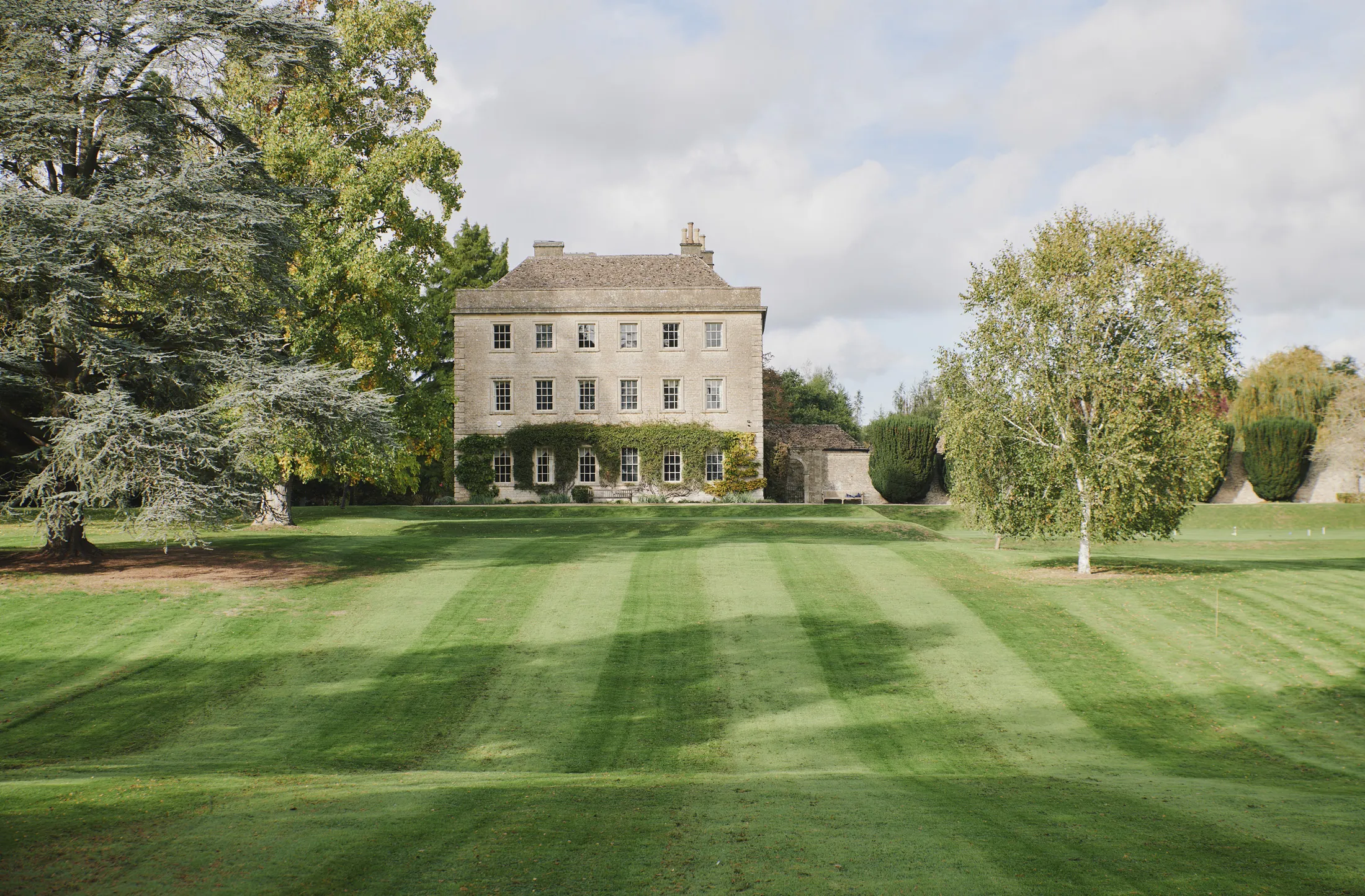 Historic Cotswold stone mansion set within manicured striped lawns and mature trees at Havenwood, a Domus Stay luxury countryside escape.