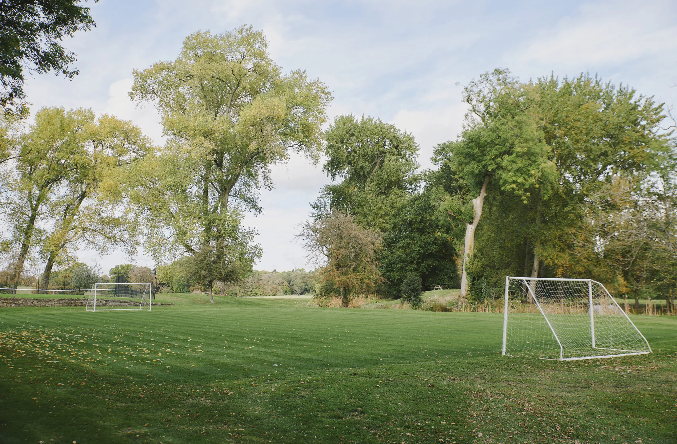 Manicured croquet lawn with vintage mallets and hoops beside historic stone building at Havenwood, a Domus Stay luxury retreat.