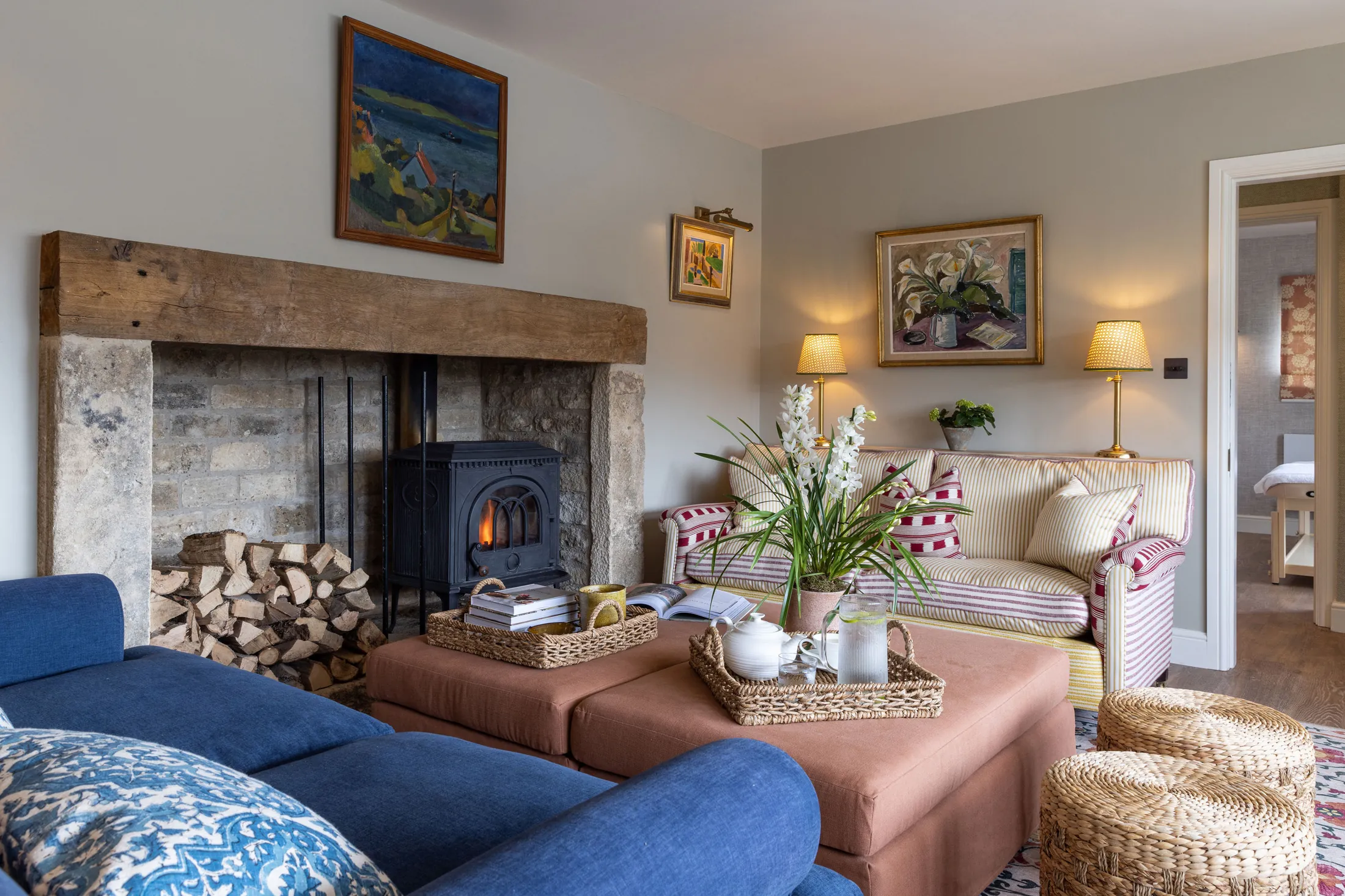 Charming sitting room with log burner, country artwork and relaxed seating at Coombe End, a premium Cotswolds holiday rental curated by Domus Stay.