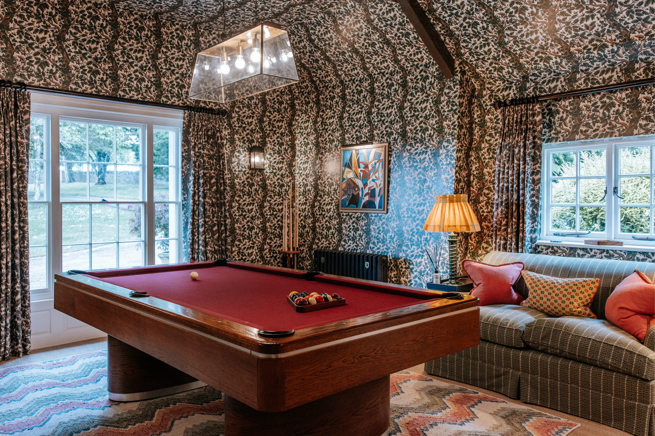 Characterful games room at Coombe End, a Domus Stay premium countryside rental, with a red pool table, patterned interiors and garden views.