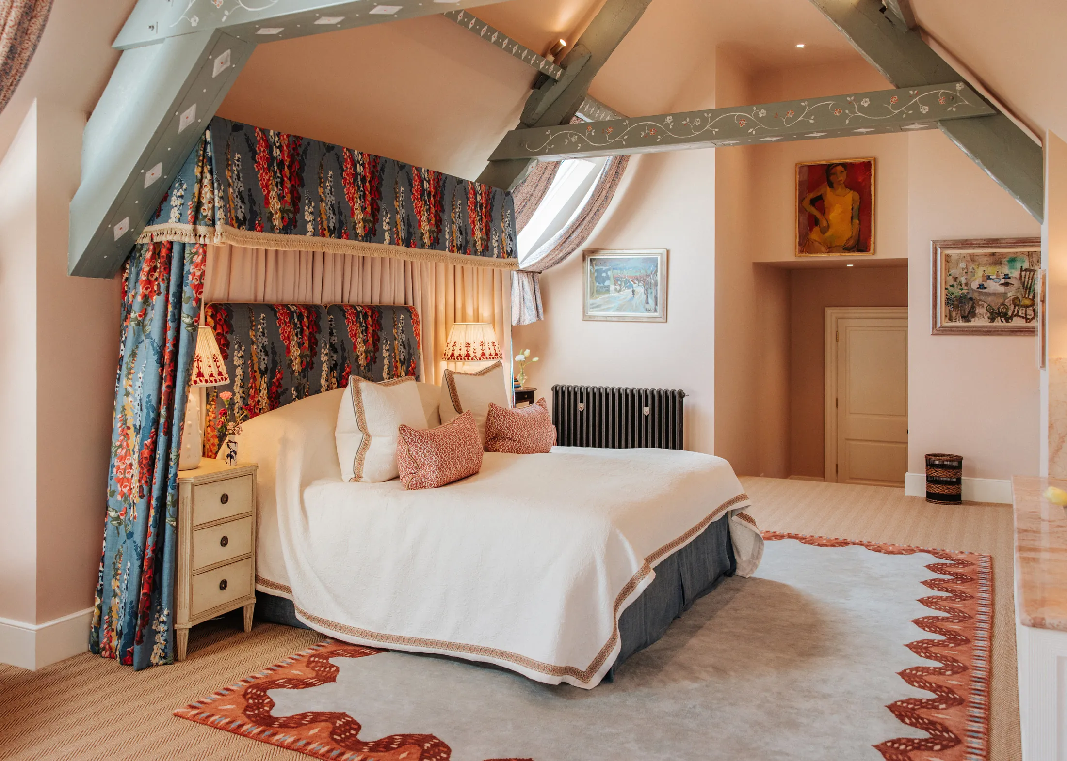 Elegant attic suite at Coombe End, a Domus Stay luxury holiday home, featuring a canopied bed, exposed beams and soft pastel tones.