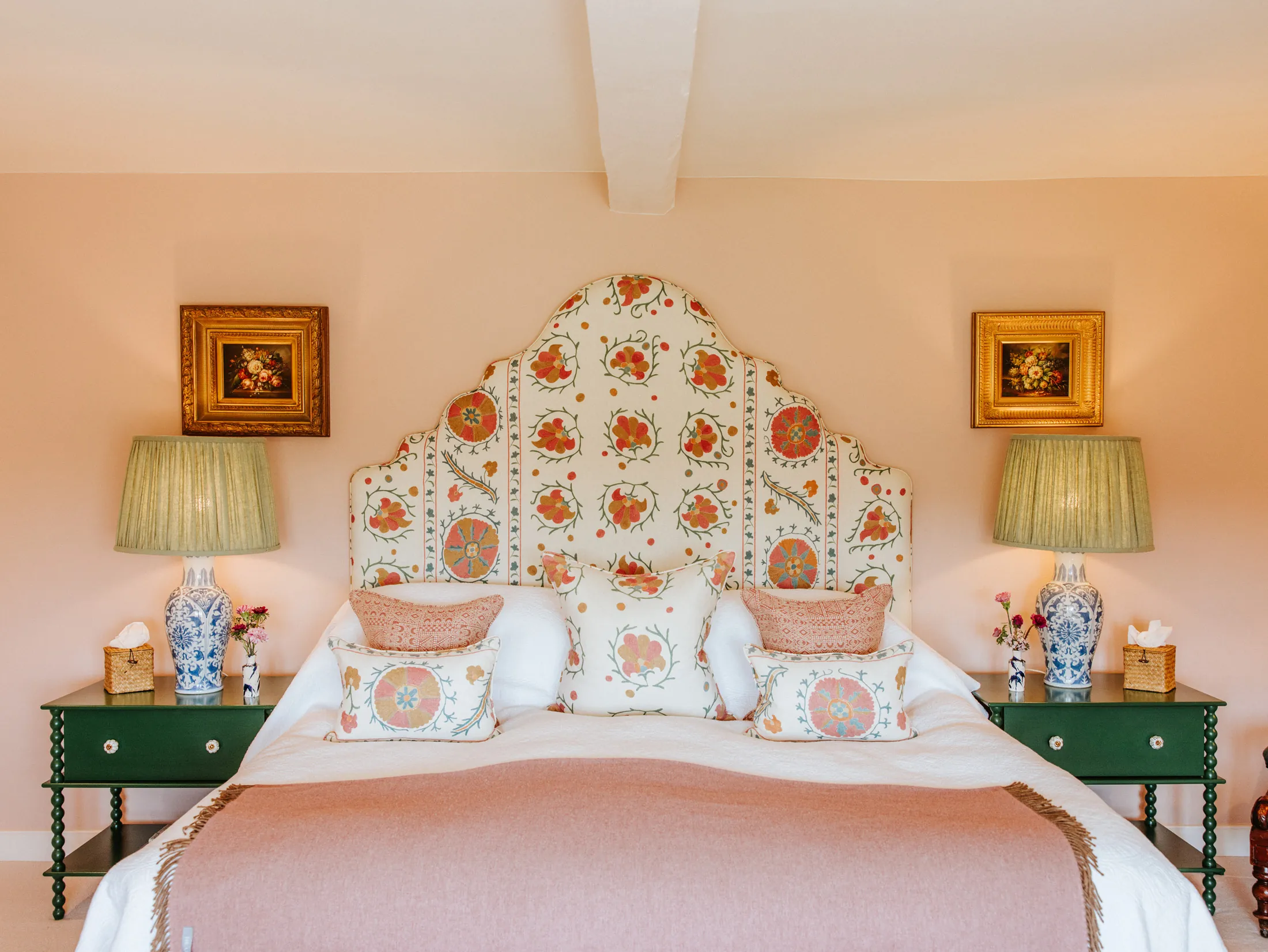 Elegant bedroom at Coombe End, a Domus Stay luxury holiday property, showcasing a patterned canopy headboard, classic bedside lamps and green accents.