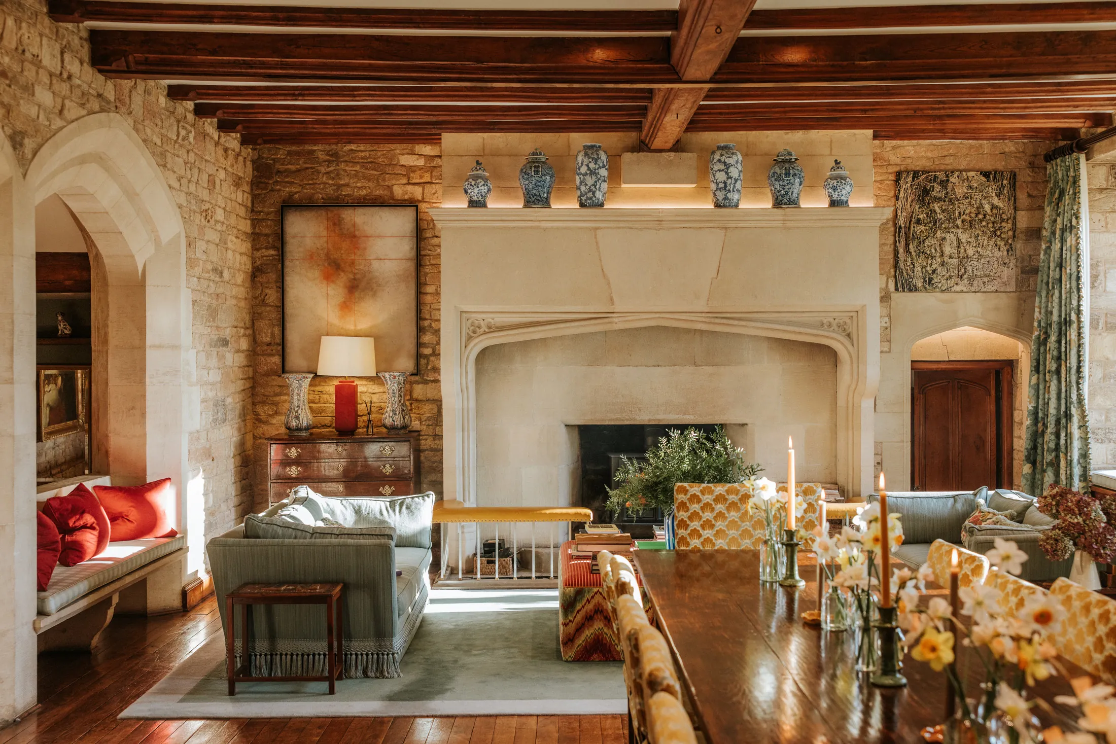 Elegant drawing room at Coombe End, part of the Domus Stay luxury rental portfolio, featuring a stone fireplace, timber beams and richly textured seating.