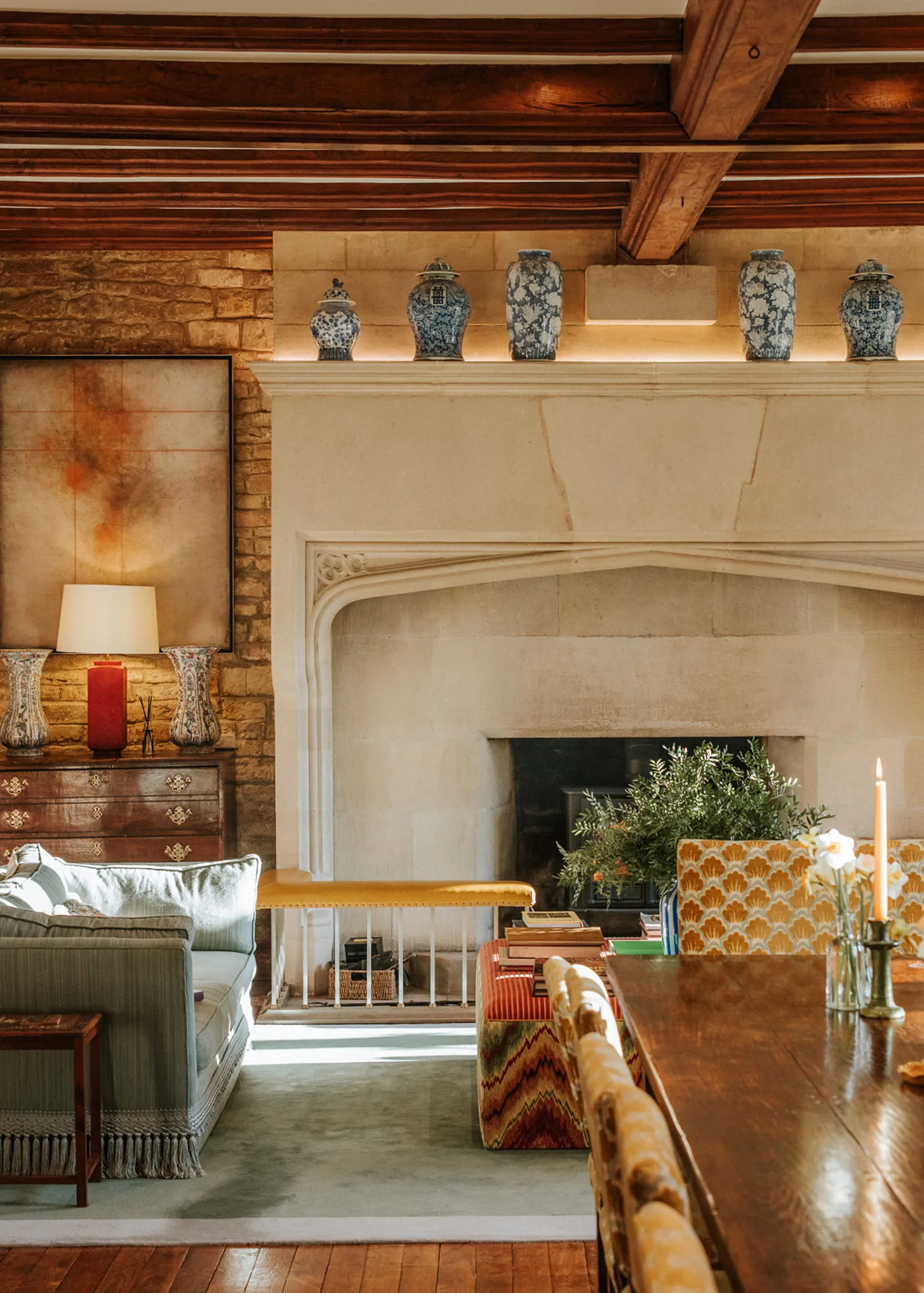 Elegant stone fireplace with blue-and-white vases and warm furnishings at Coombe End, presented as a luxury Domus Stay short-stay rental in the Cotswolds.