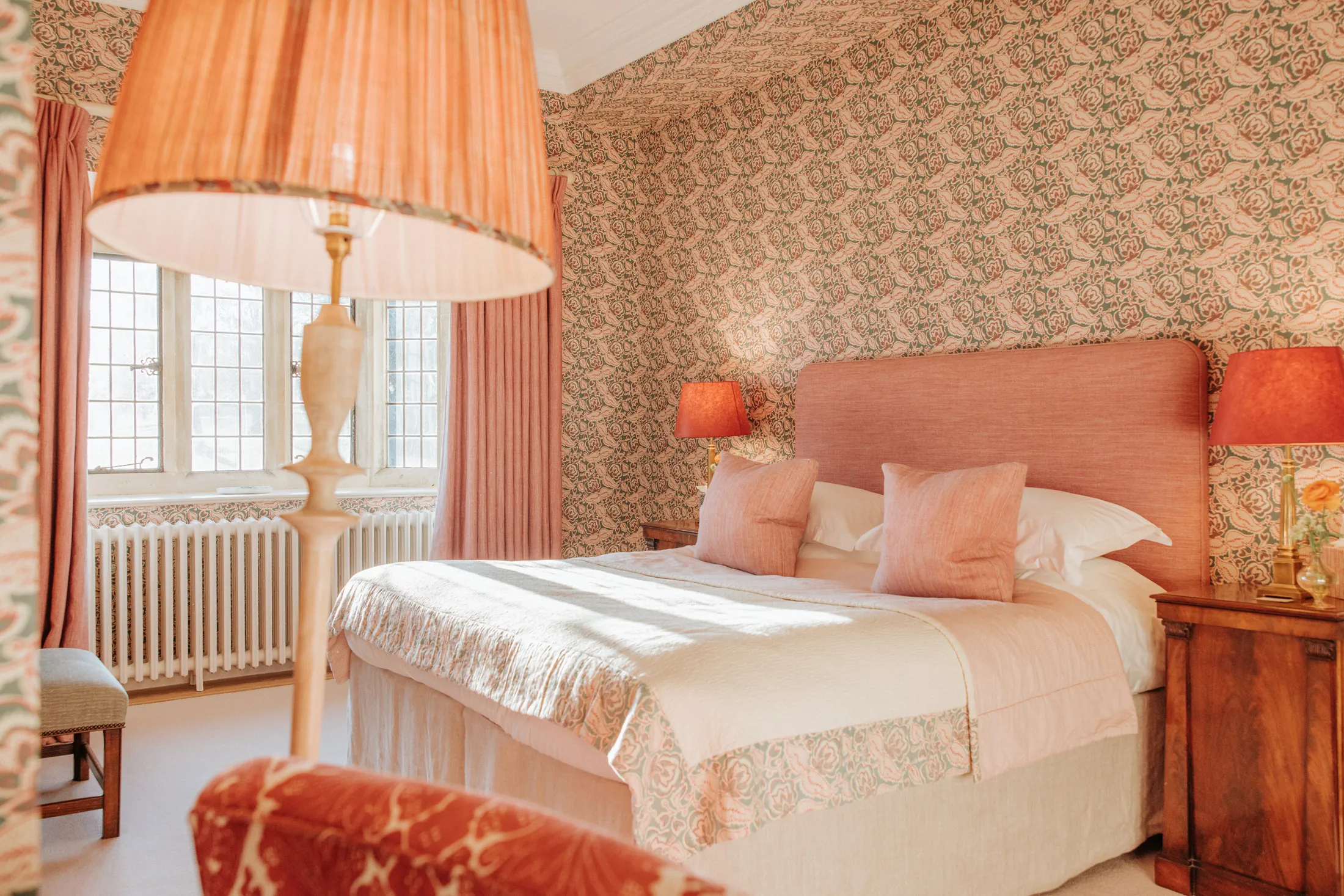 Warm, rose-toned bedroom at Coombe End, part of the Domus Stay premium rental portfolio, with patterned wallpaper, soft furnishings and morning light.