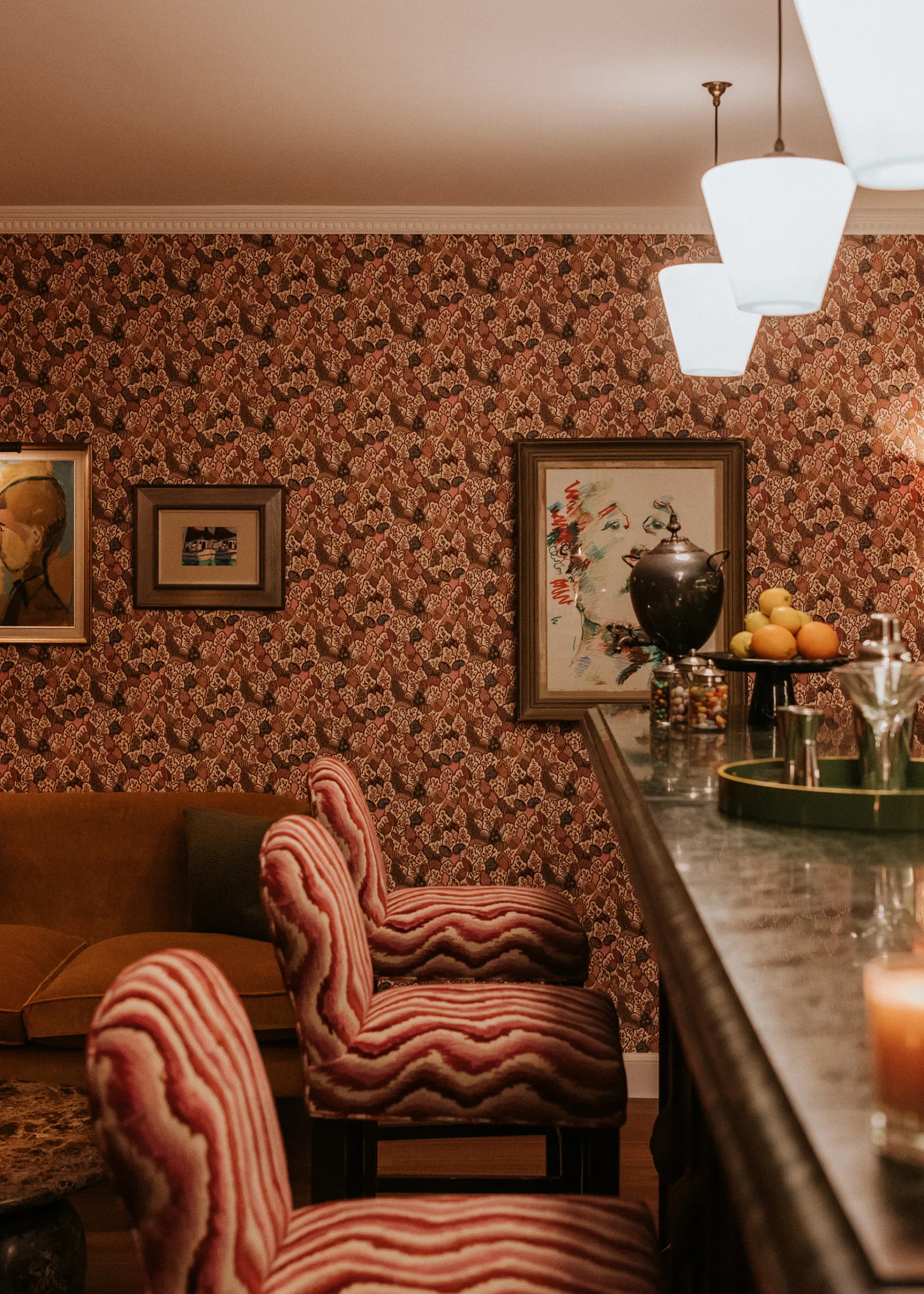 Intimate bar-lounge detail with patterned stools, warm lighting and vintage art at Coombe End, a distinctive Cotswolds short-stay property by Domus Stay.