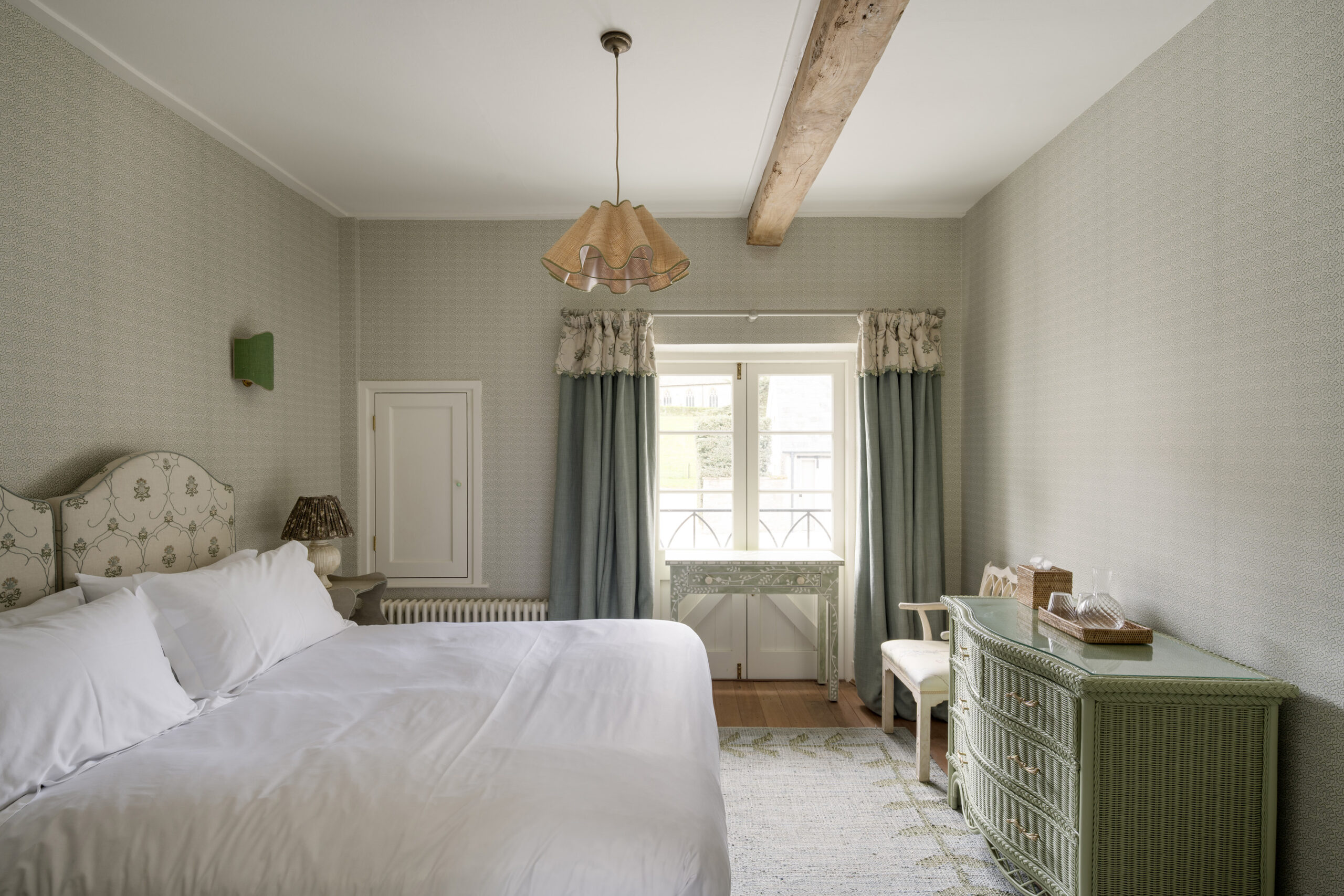 Elegant en-suite bedroom at Ford Cottage, with soft sage tones, patterned headboard and garden views, offered by Domus Stay as a luxury short-stay rental in The Cotswolds.