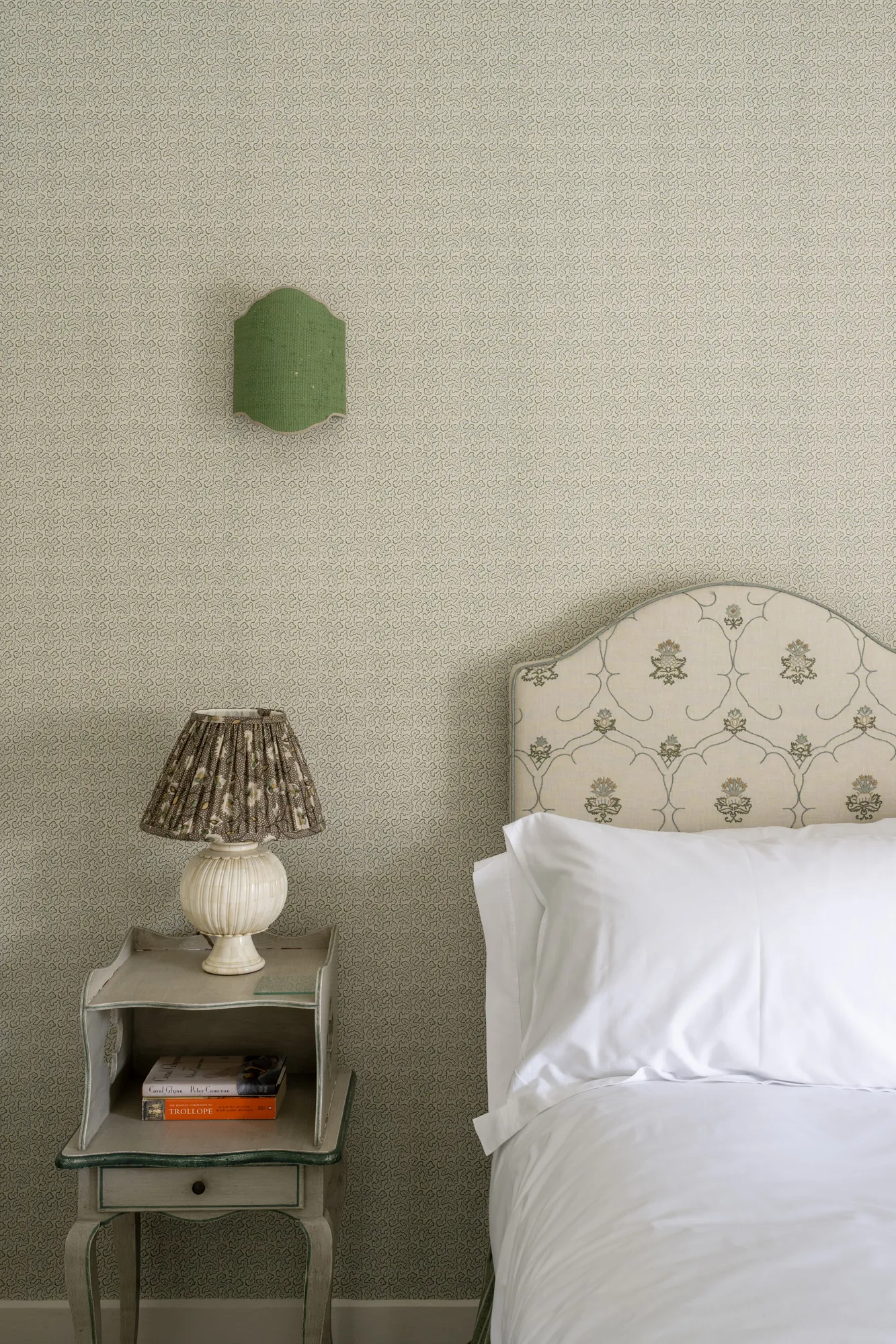 Detail of bedside table and patterned headboard in a Ford Cottage bedroom, showcasing refined textures and heritage styling, offered by Domus Stay as a luxury short-stay rental in The Cotswolds.